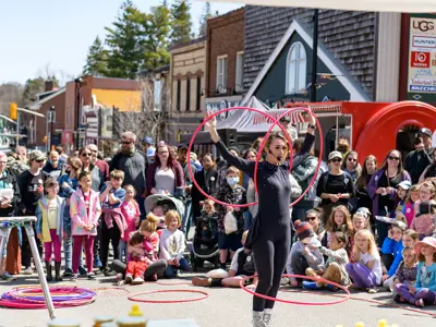 Performer with multiple hulahoops entertaining outdoor crowd