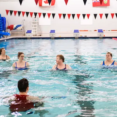 swimming instructor teaching class of four at indoor swimming pool