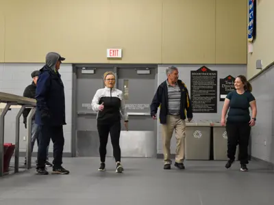 four individuals walking and talking together on indoor track