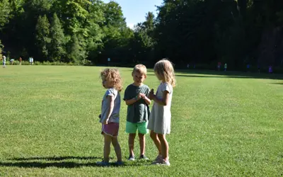 three youths standing outside on grassy field